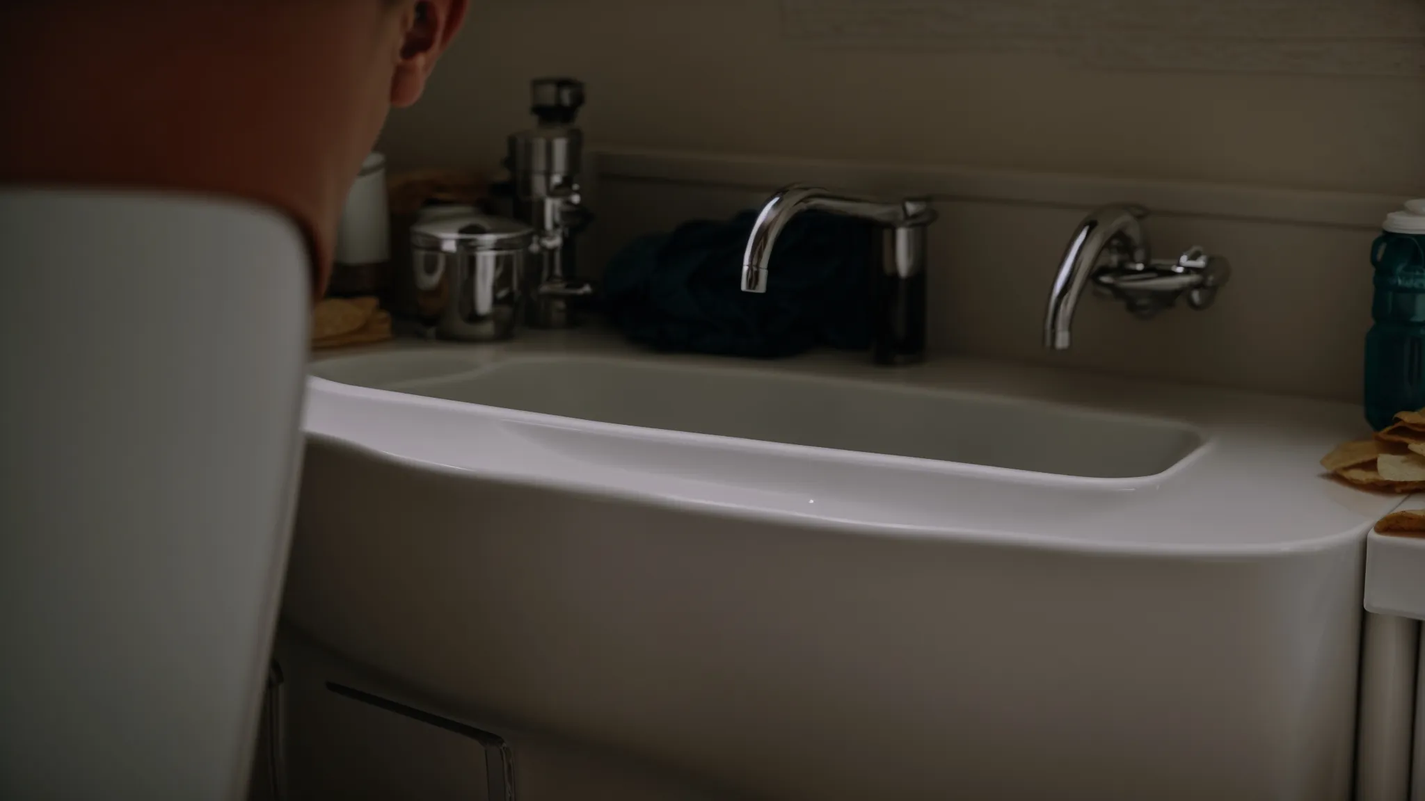 a homeowner stares at a noticeable crack along a pipe under the sink, pondering the next steps.